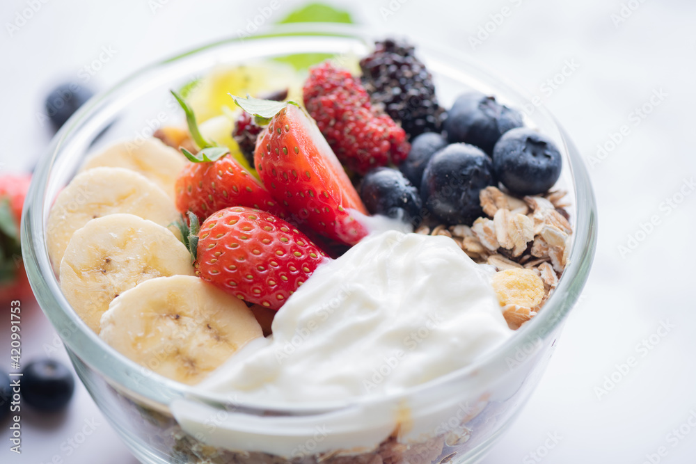 bowl of oat granola with yogurt, fresh blueberries, mulberry, strawberries, kiwi, banana, mint and nuts board for healthy breakfast, top view, copy space, flat lay. vegetarian food concept. bowl of oat granola with yogurt, fresh blueberries, mulberry, strawberries, kiwi, banana, mint and nuts board for healthy breakfast, top view, copy space, flat lay. vegetarian food concept.