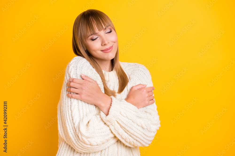 Portrait of pretty lady hugging shoulder closed eyes imagination wear knitted pullover isolated on yellow color background Portrait of pretty lady hugging shoulder closed eyes imagination wear knitted pullover isolated on yellow color background