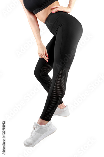 Cropped image of a female model in tight black leggings take a side step, over white background.