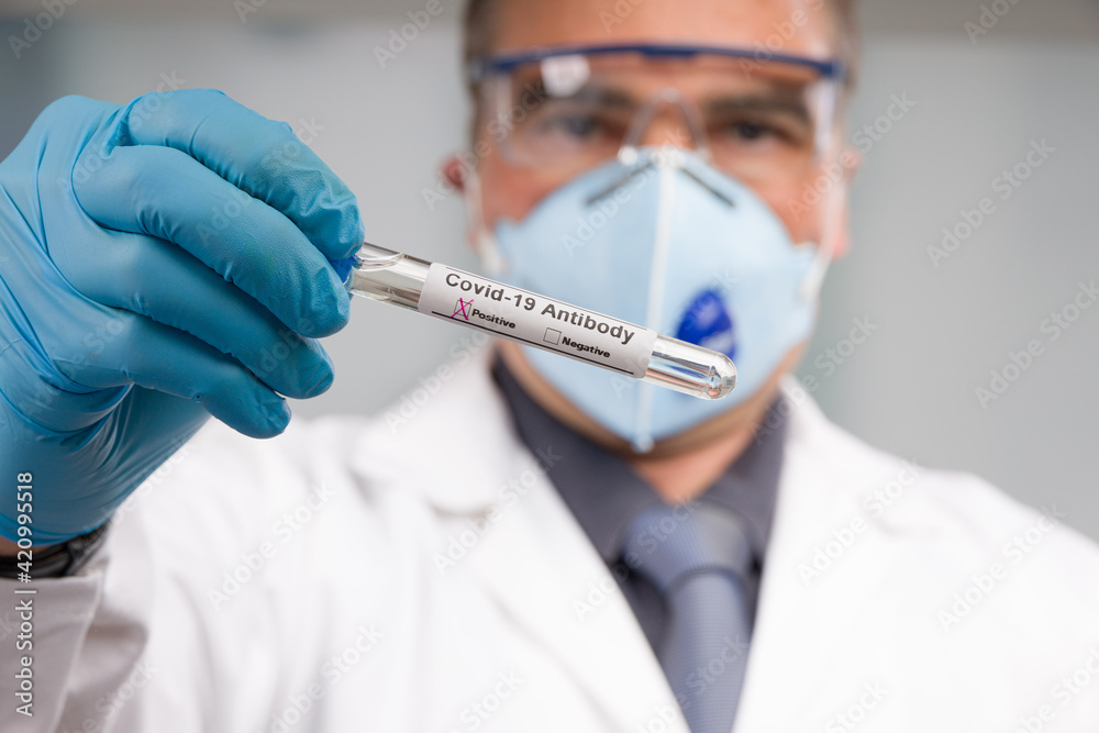 Doctor with medical face mask and medical gloves is handling a positive corona antibody test Doctor with medical face mask and medical gloves is handling a positive corona antibody test