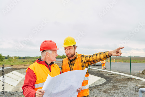 Bauleiter und Architekt mit Bauzeichnung auf Baustelle