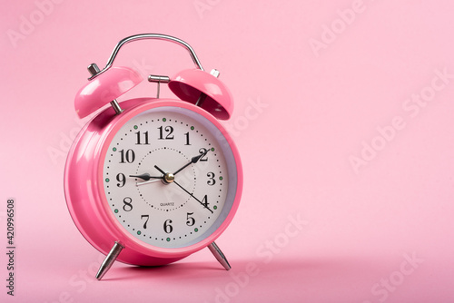 A pink table clock with a Pink background flat lay shot