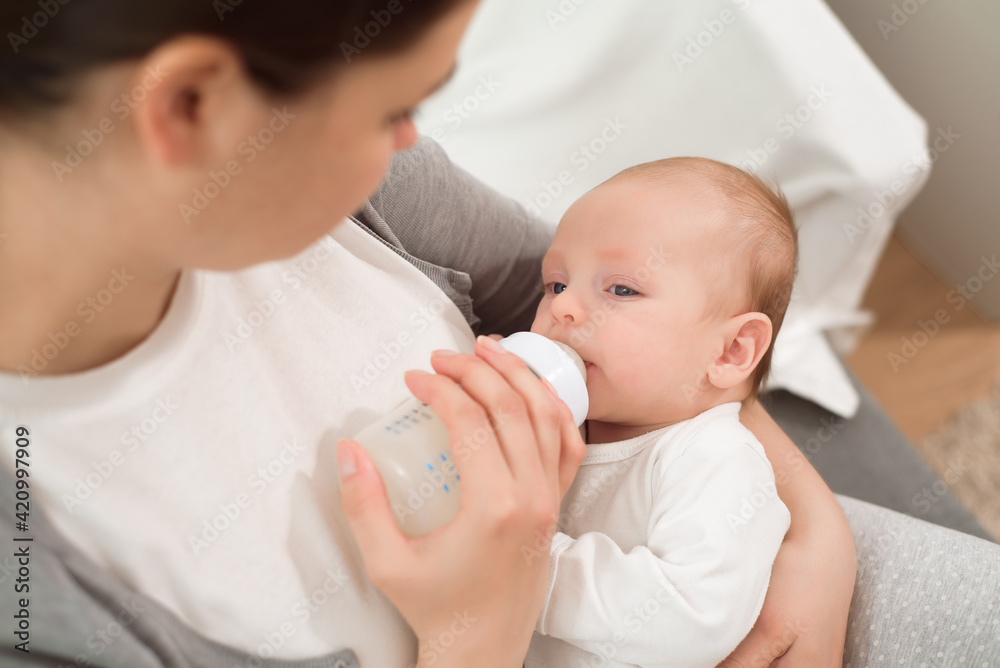 Woman holding a newborn baby in her arms and feeds him from a milk bottle. Woman holding a newborn baby in her arms and feeds him from a milk bottle.