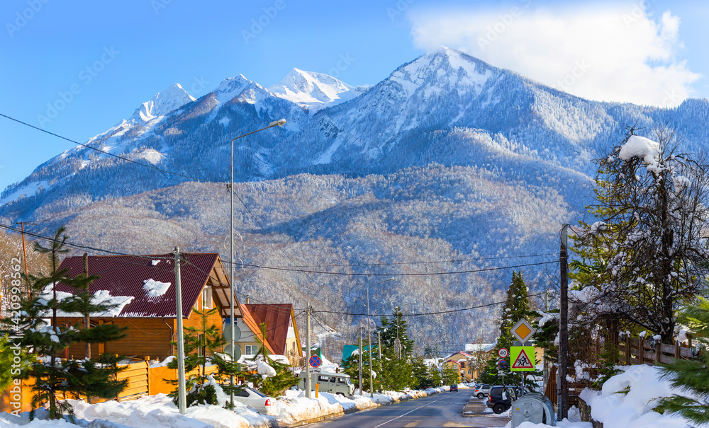 Krasnaya Polyana village, Sochi, Russia - Houses and a street on the background of the Caucasus Mountains