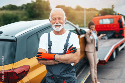 Handsome senior man working in towing service on the road. Roadside assistance concept.