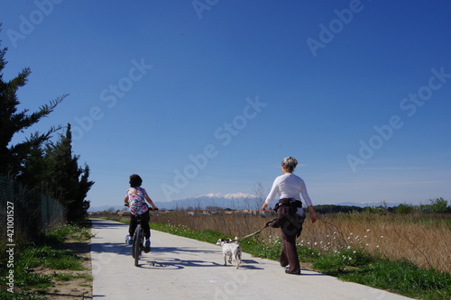 Maman et enfant à vélo et chien sur une piste cyclable voie verte