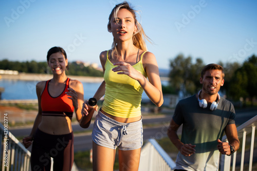 Athletic fit people exercising and running together outdoors