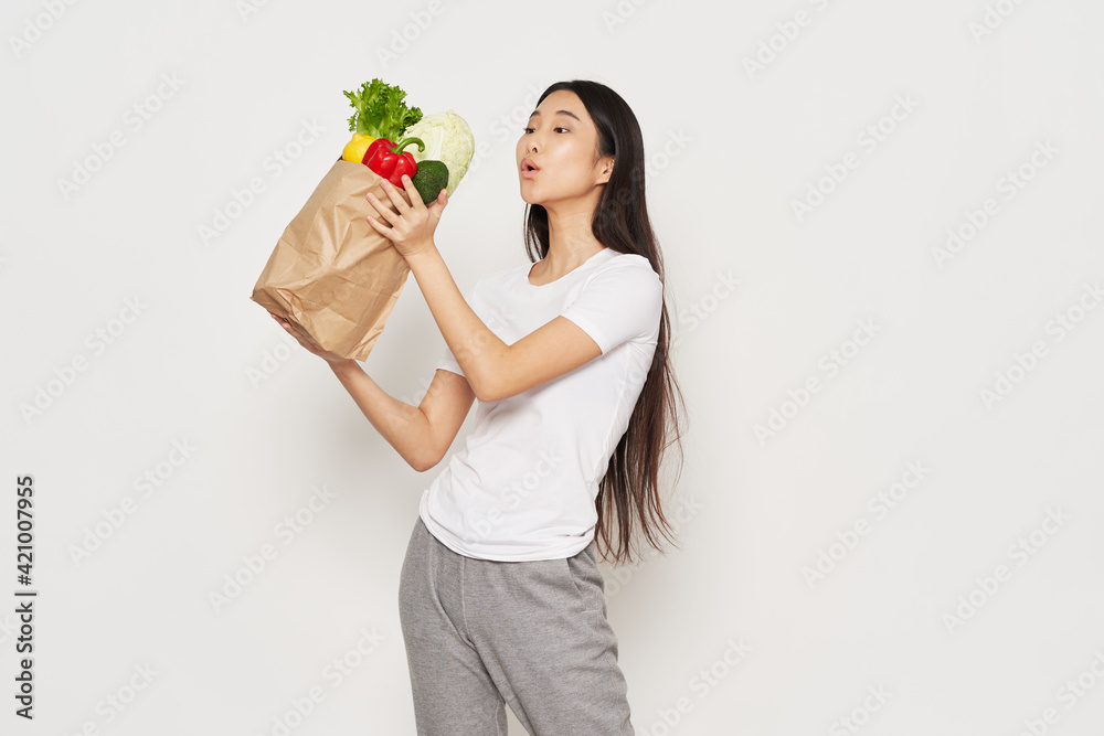 Slender woman in sportswear holds in her hand a packet with vegetables calorie Slender woman in sportswear holds in her hand a packet with vegetables calorie