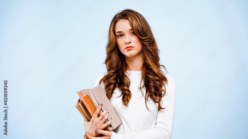 curly young woman holding books isolated on blue curly young woman holding books isolated on blue
