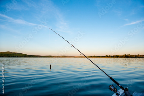 Fishing rod spinning with the line close-up. Fishing rod in rod holder in boat due the fishery day at the sunset. Rod rings. Fishing tackle. Fishing spinning reel.