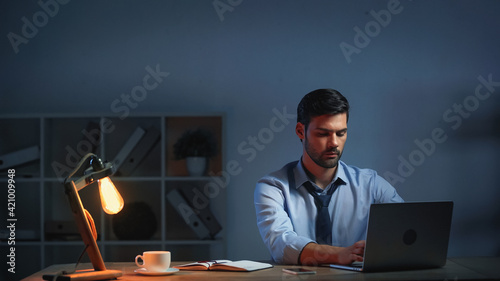 businessman in suit using laptop while working late in office