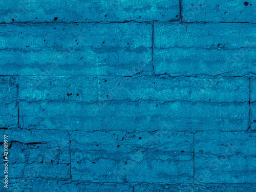 Brickwork of bright blue geometric horizontal bricks bonded with cement grout between square stones. Wall exterior. Background