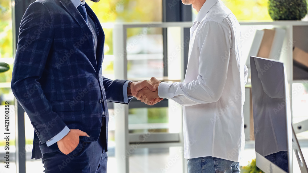 cropped view of businessmen shaking hands in office
