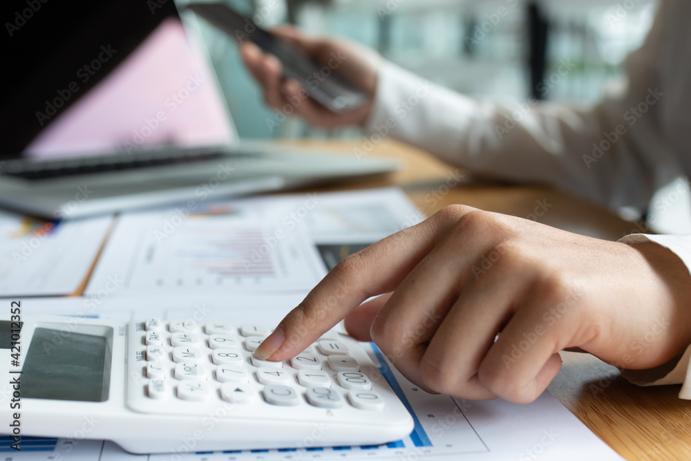 Closeup of female who are using their fingers to press the calculator for calculating bills in the office.finance report. Business office concept. Closeup of female who are using their fingers to press the calculator for calculating bills in the office.finance report. Business office concept.