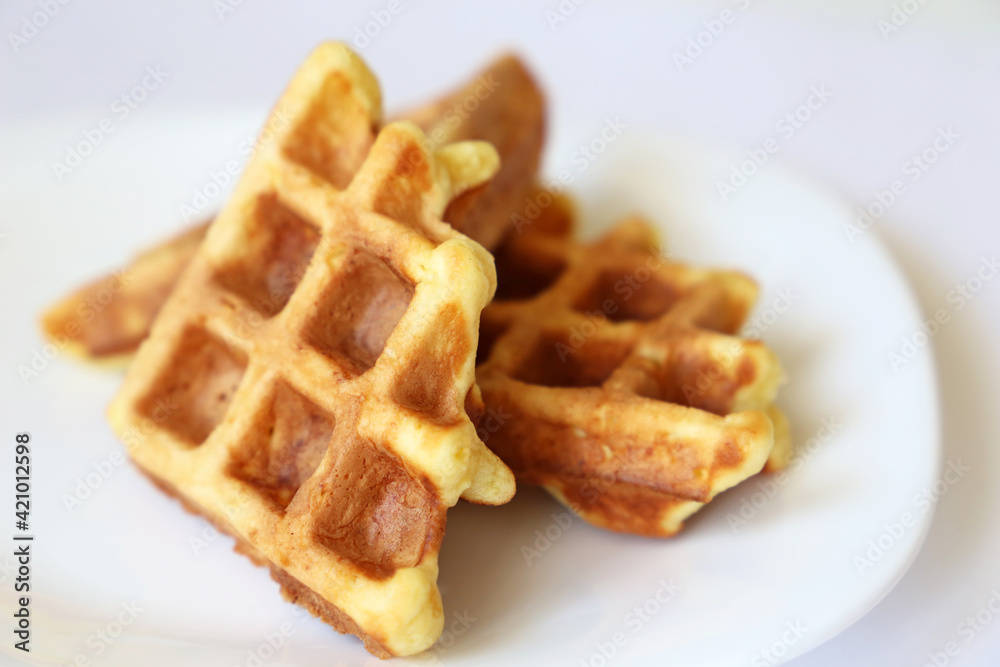 Belgian waffles in white plate. Healthy breakfast close up, pieces of freshly baked classic wafer Belgian waffles in white plate. Healthy breakfast close up, pieces of freshly baked classic wafer