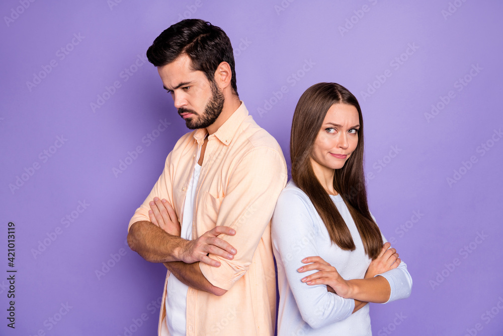 Photo of unhappy couple guilty woman sad man folded hands stand back to back isolated on purple color background Photo of unhappy couple guilty woman sad man folded hands stand back to back isolated on purple color background