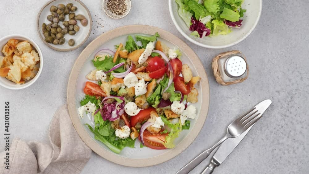 Serving healthy vegetarian salad on a plate. Healthy italian style salad ala Panzanella with tomatoes, croutons, lettuce and mozzarella. Top view Serving healthy vegetarian salad on a plate. Healthy italian style salad ala Panzanella with tomatoes, croutons, lettuce and mozzarella. Top view