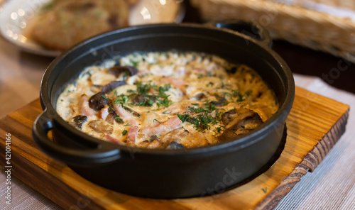 fried pieces of meat with vegetables and bechamel sauce baked in cast iron skillet