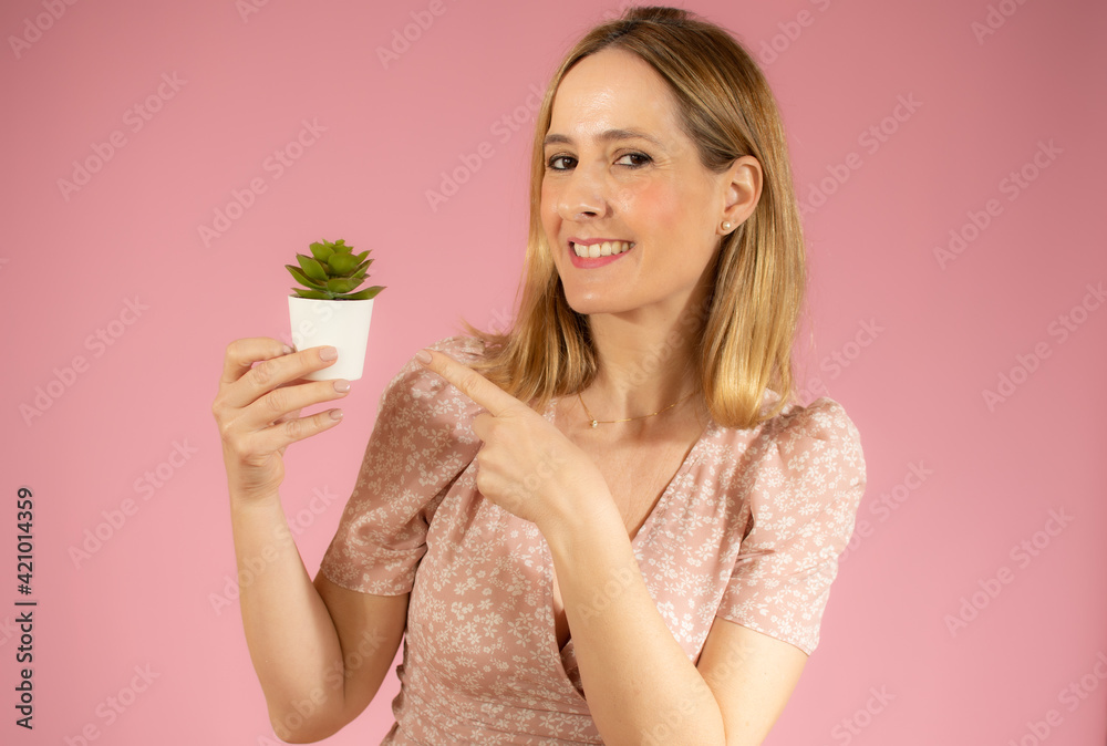 Young beautiful woman holding small plant pot over isolated pink background Young beautiful woman holding small plant pot over isolated pink background