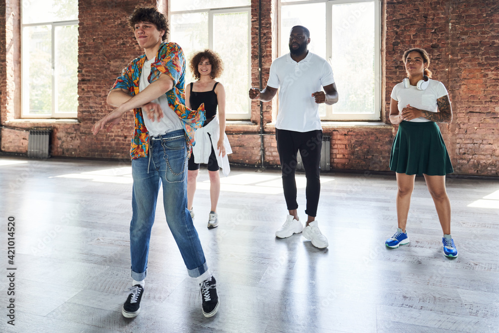 Fototapeta premium Cheerful young male teaching group of hip-hop