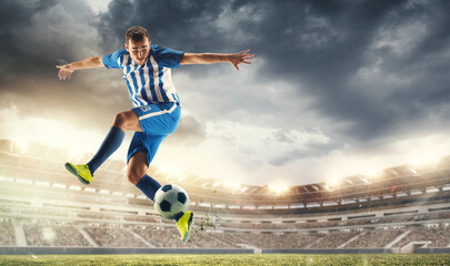 Male football or soccer player at stadium in flashlight. Young male sportive model training. Moment of attacking, catching. Concept of sport, competition, winning, action, motion, overcoming. Flyer.