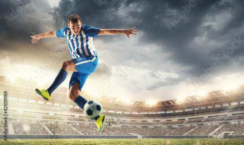 Male football or soccer player at stadium in flashlight. Young male sportive model training. Moment of attacking, catching. Concept of sport, competition, winning, action, motion, overcoming. Flyer. © master1305