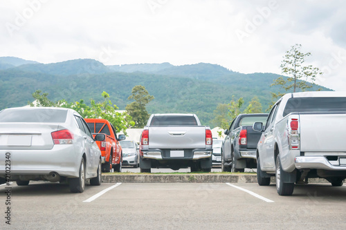 Car parked in asphalt parking lot and empty space for car park in nature with trees and mountain background .Outdoor parking lot