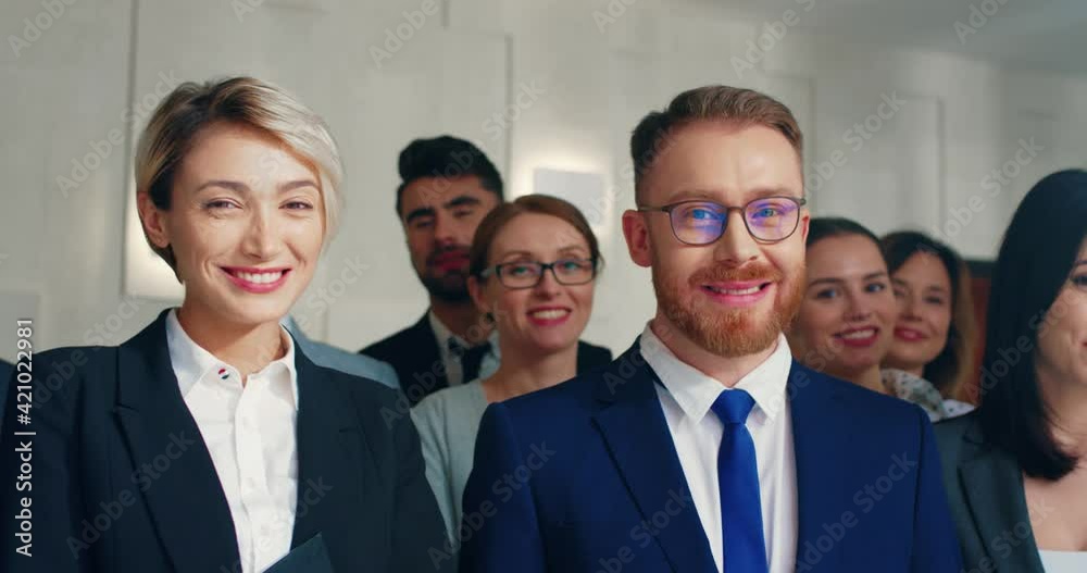 Portrait of successful business group of different ages and nationalities standing after conference and smiling looking at camera.