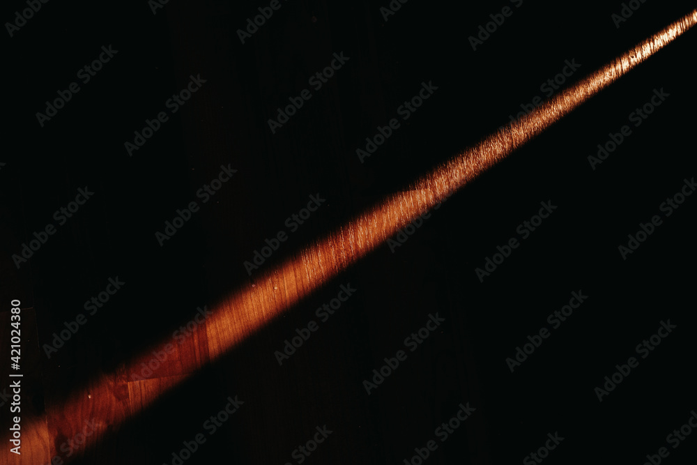 Fototapeta premium A beam of light on a black background falls on a wooden floor