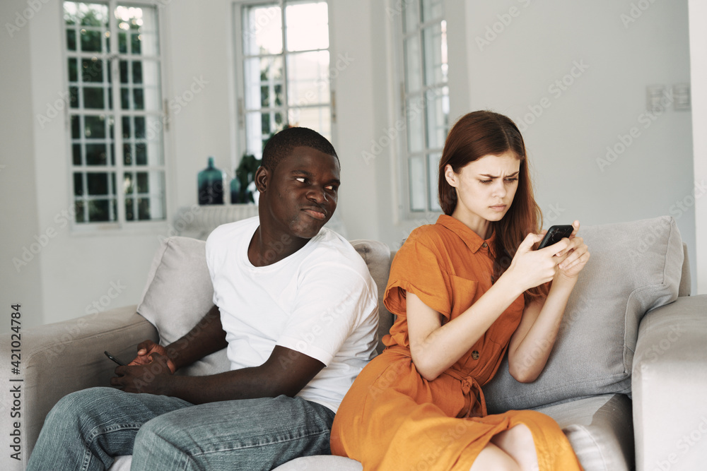 A woman examines a mobile phone and a man of African appearance A woman examines a mobile phone and a man of African appearance