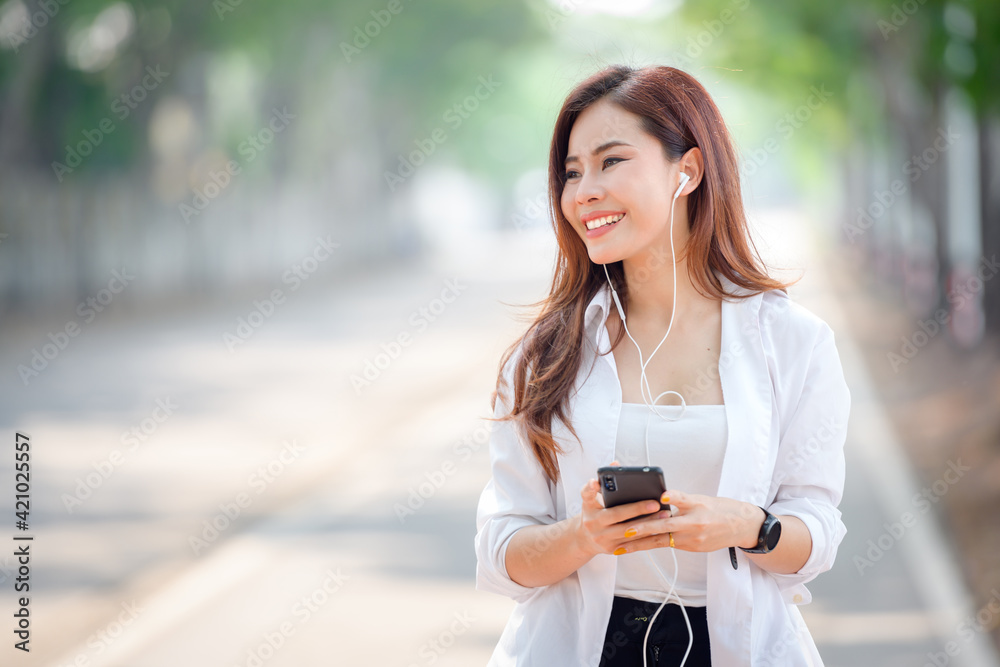 Happy asian beautiful woman Walking and using a smartphone on the street on a sunny hot summer day in the park. Happy asian beautiful woman Walking and using a smartphone on the street on a sunny hot summer day in the park.