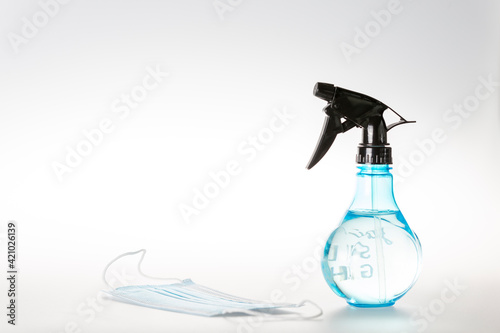 Mask and bottle of water with a spray on white background 