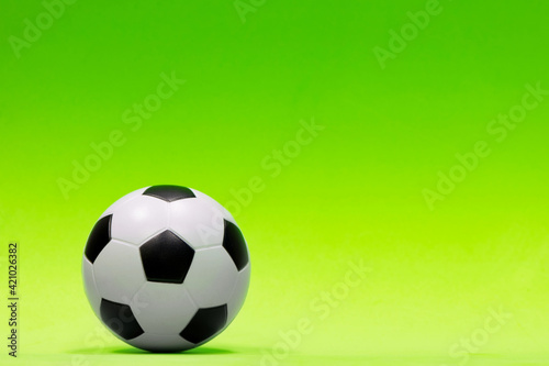Soccer ball isolated against a plain green background with gradual color shading. Conceptual image with copy space on the right side.
