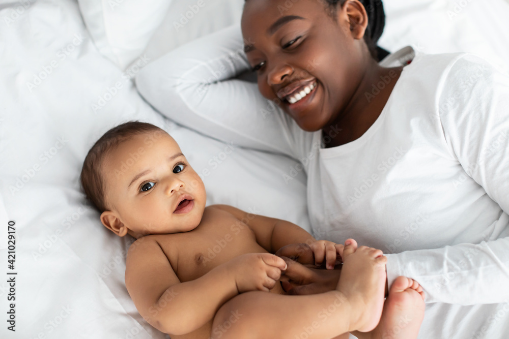 African American mom lying in bed with her cute infant