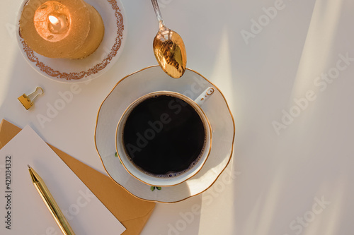 Still life composition with coffee in a retro cup, candle and golden pen