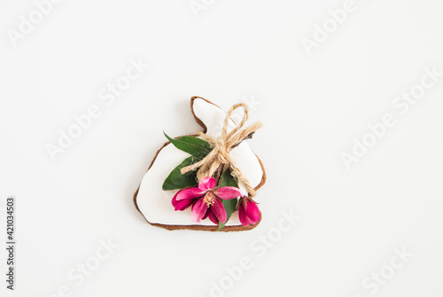 Flat lay of Easter gingerbreads bunny shape, green leaves and pink flowers. Minimalist Easter. White background. Happy Easter card.