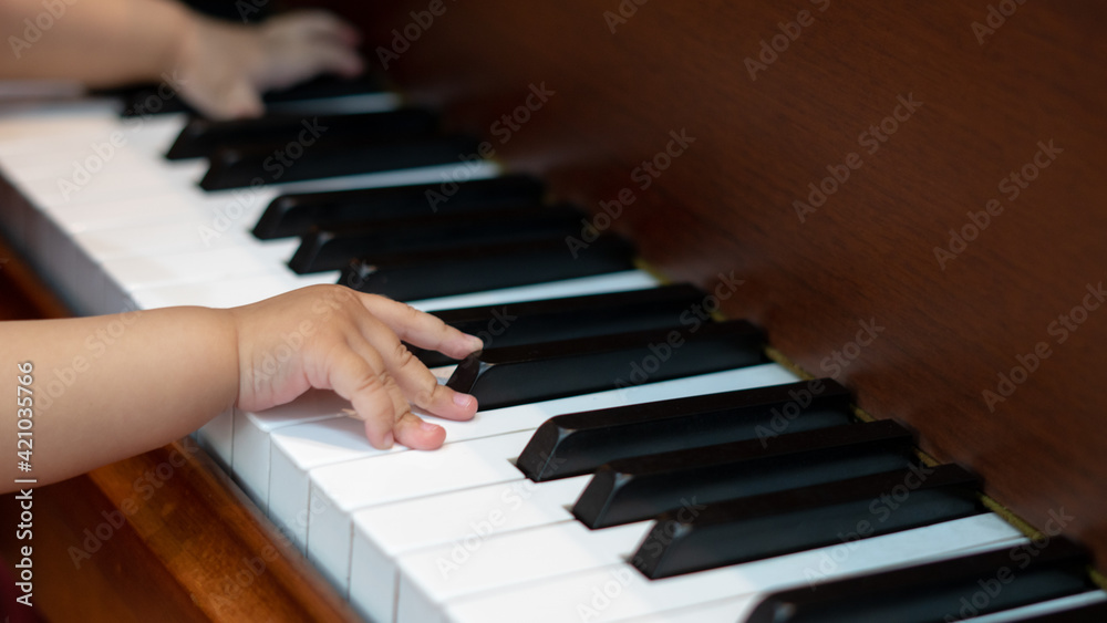 Side view of Baby Girl's Hands playing with Piano Keys with an adult