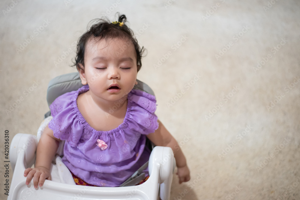 Fototapeta premium Cute little asian baby girl Sitting asleep on the dining table After eating full in the house
