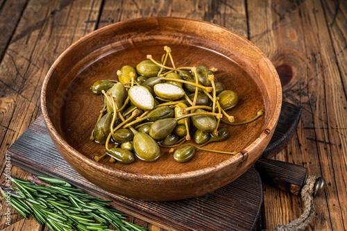 Salted capers in vinegar in a wooden plate. wooden background. Top view