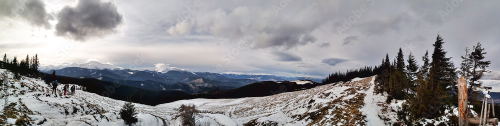 Panorama on the sunny winter day in the Carpathian mountains. Breathtaking view of snow-capped peaks, tourists and Mount Hoverla. Scenic conceptual landscape.