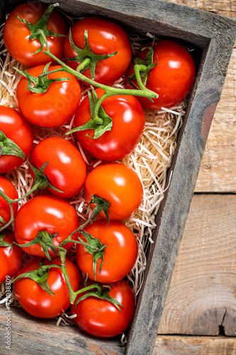 Red tomatoes in wooden market box. Wooden background. Top view