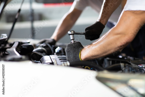 Caucasian male mechanic repairs car in garage. Car maintenance and auto service garage concept. Closeup hand and spanner. © NVB Stocker