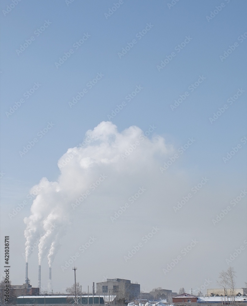 winter white smoke from chimneys on blue sky background