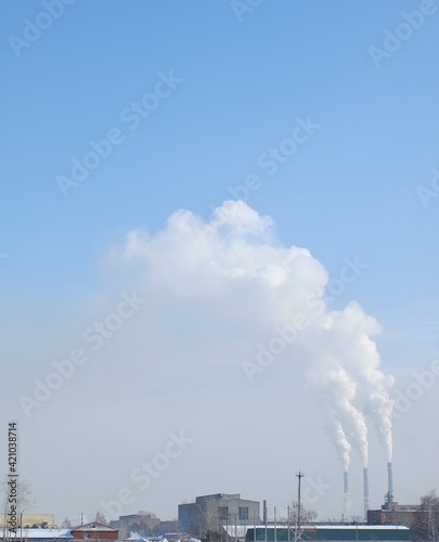 winter white smoke from chimneys on blue sky background