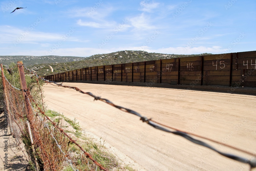 Border between the United States and Mexico, near Campo, California and Tecate, Mexico. Barbed wire and a rusty metal wall with numbers 44 and up. As seen from the American side of the border. 