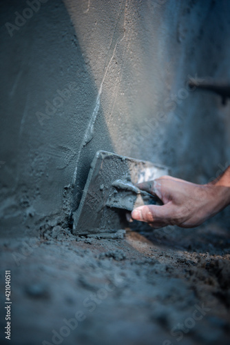 Close-up hand of worker Plastering cement wall for building the house with sunlight, Concept Construction.