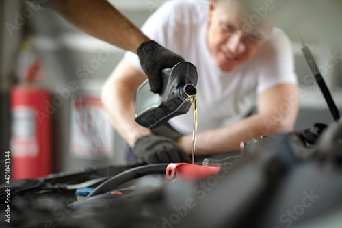 Pouring oil to car engine. Closue up male mechanic hand working  and service in Car Service station