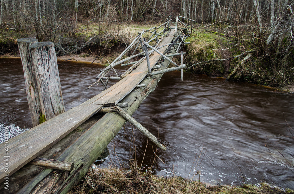 Old broken wooden dangerous bridge over Riezupe river, Latvia