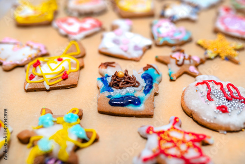Hand decorated baked gingerbreads of various shapes, arranged on baking paper.