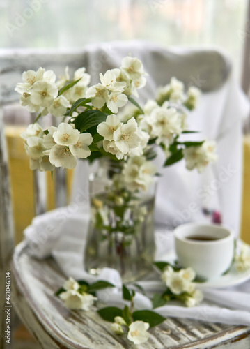 Jasmine flowers in a glasse vase. Stillife with jasmine and cup of coffee.
